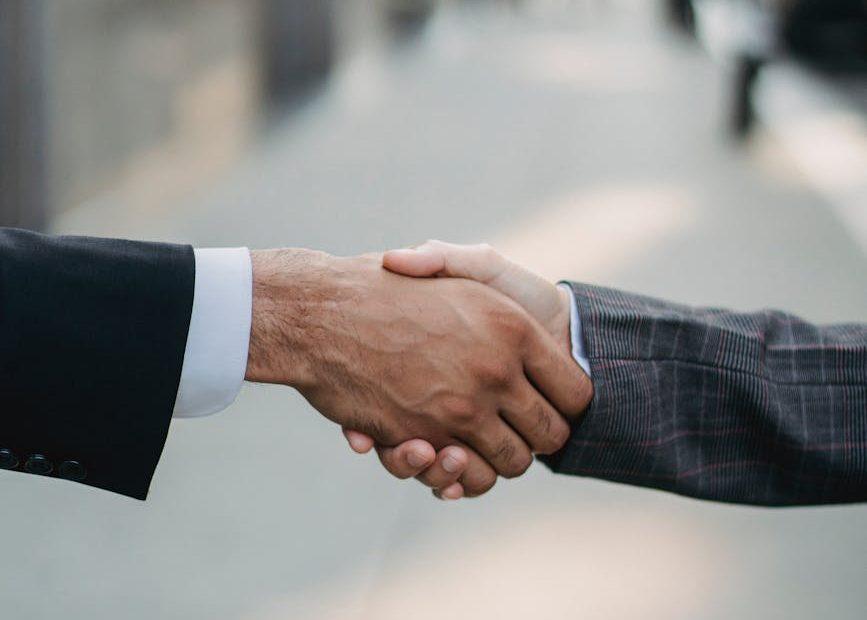 Two businesspeople shake hands, symbolizing a business partnership.